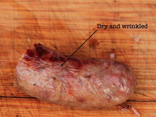 Half a cooked sausage, with a label pointing out its dry and wrinkled exterior