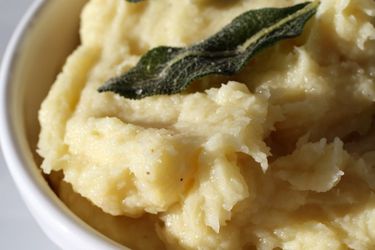 A bowl of parsnip puree with olive oil and sage. 