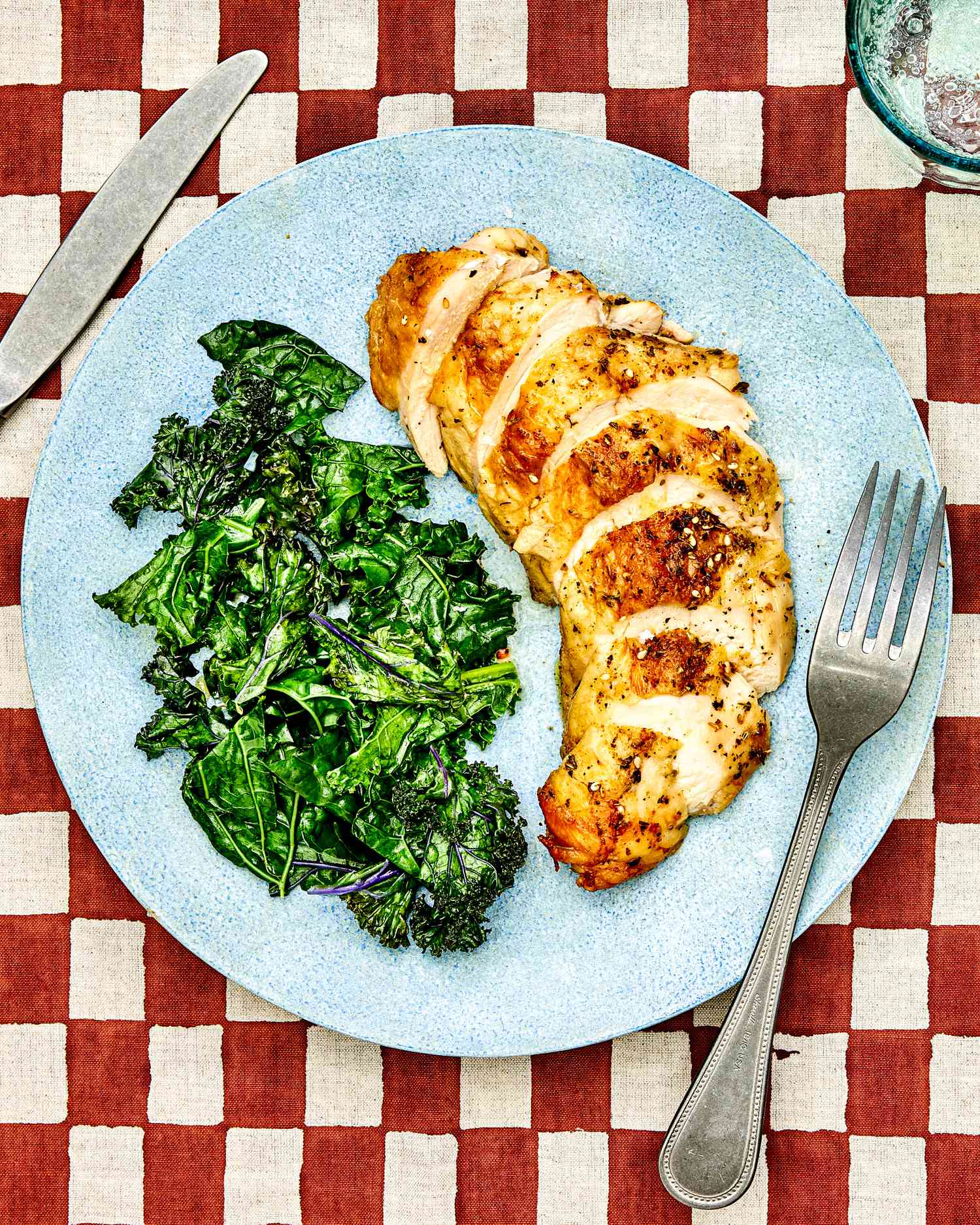 Sliced chicken breast and sautéed kale on a blue palte.