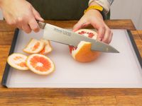 a person removing the peel from a grapefruit on the oxo board