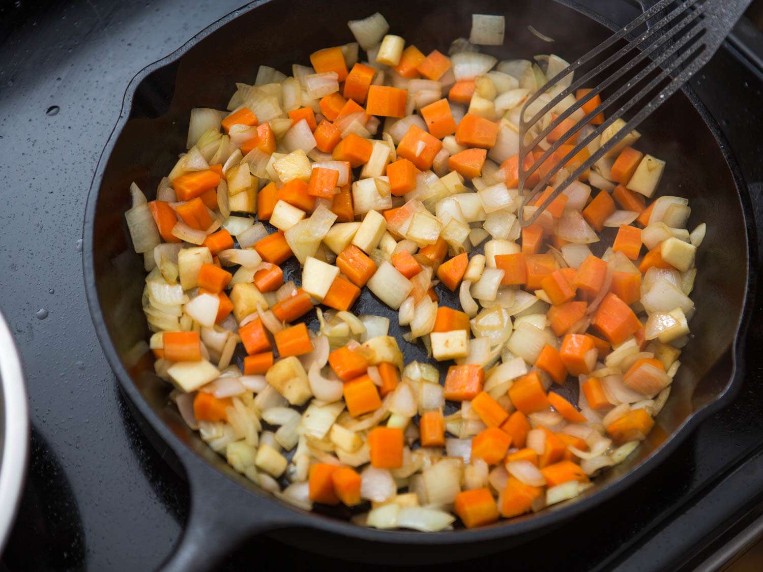 Sauteeing diced carrot, parsnip, and onion in a skillet