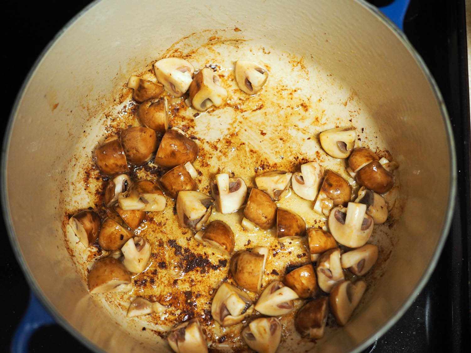 Quartered mushrooms are browned in the Dutch oven.