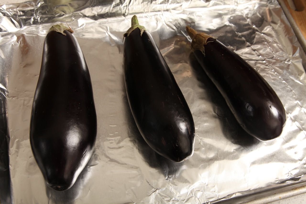 Three eggplants on a foil-rimmed baking sheet