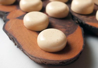 Several eggnog jello shots served on a live-edge platter make of hardwood.