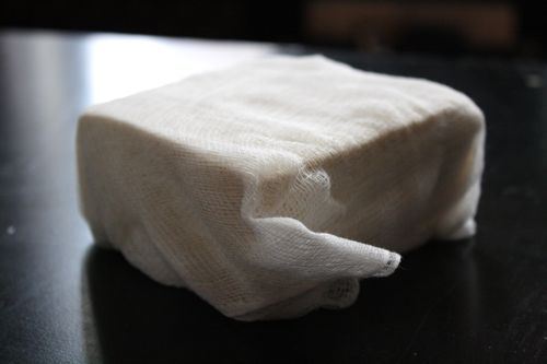 A block of tofu wrapped in cheese cloth. 