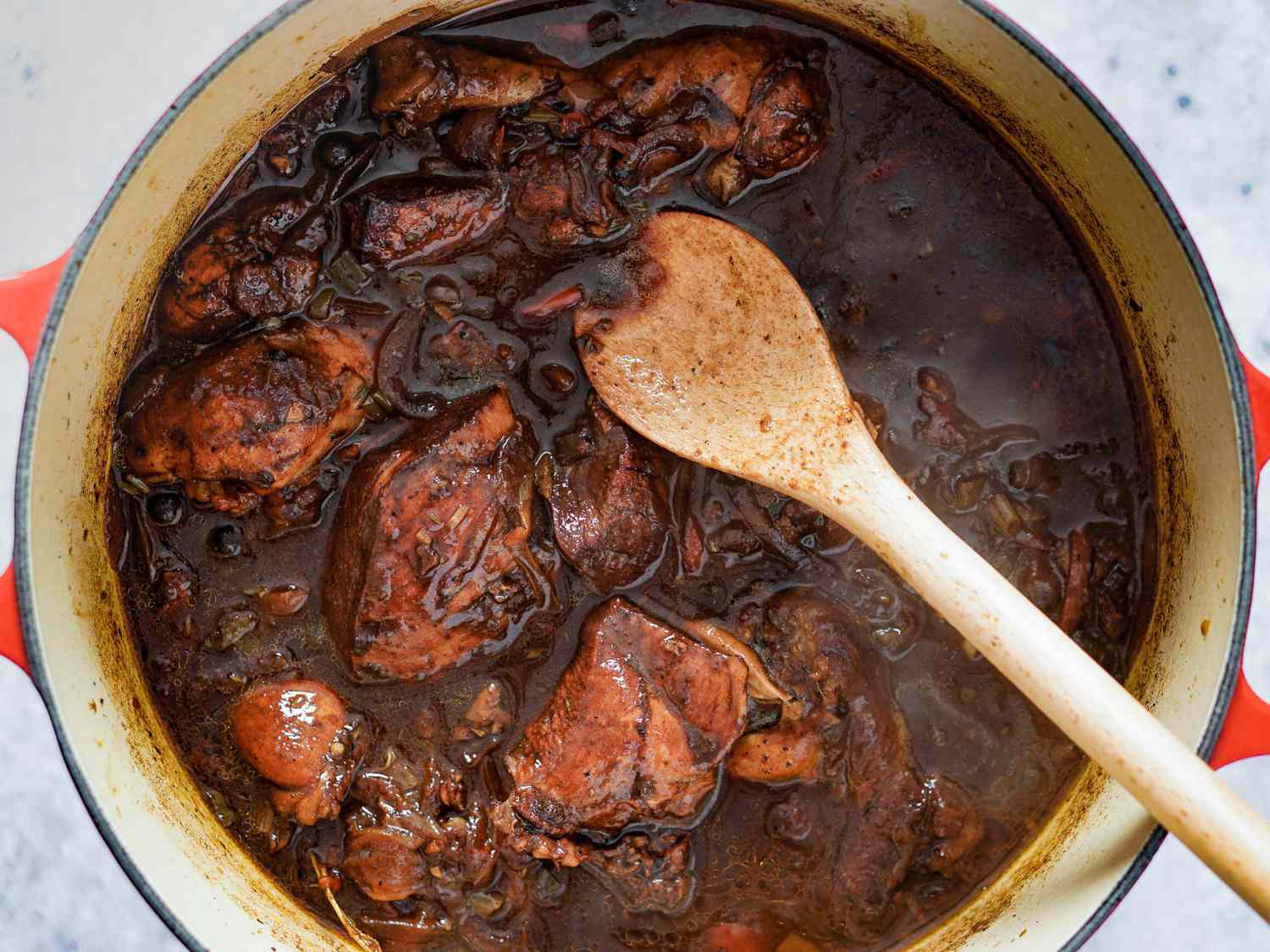 Stirring ketchup into brown stew chicken