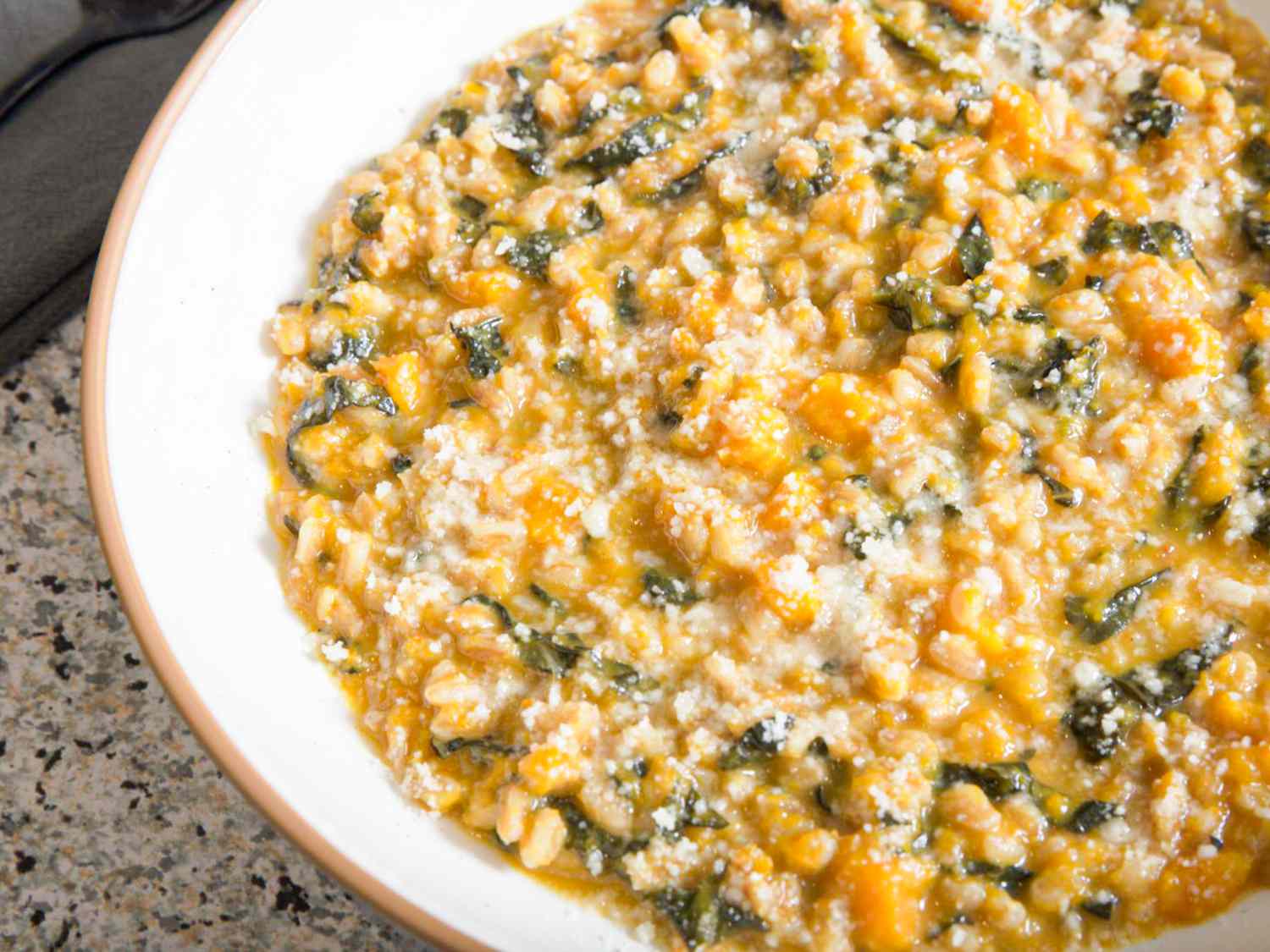 Close up of Butternut Squash Farrotto in a white bowl on a tile surface 