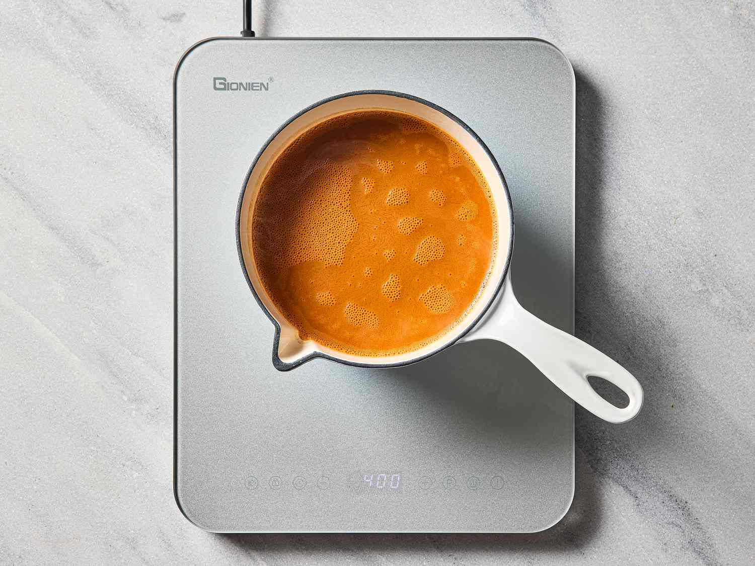 A saucepan containing simmering liquid placed on an induction cooktop