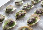 A baking sheet of Oysters Rockefeller resting on a layer of rock salt