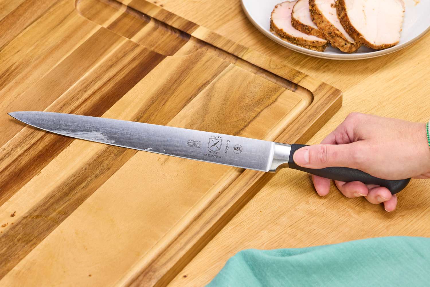 A person holds the Mercer Culinary 10-Inch Carving Knife
