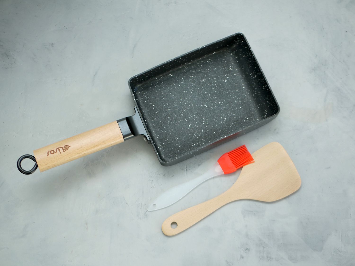 lisos tamagoyaki pan with silicone brush and wooden spatula on a gray surface