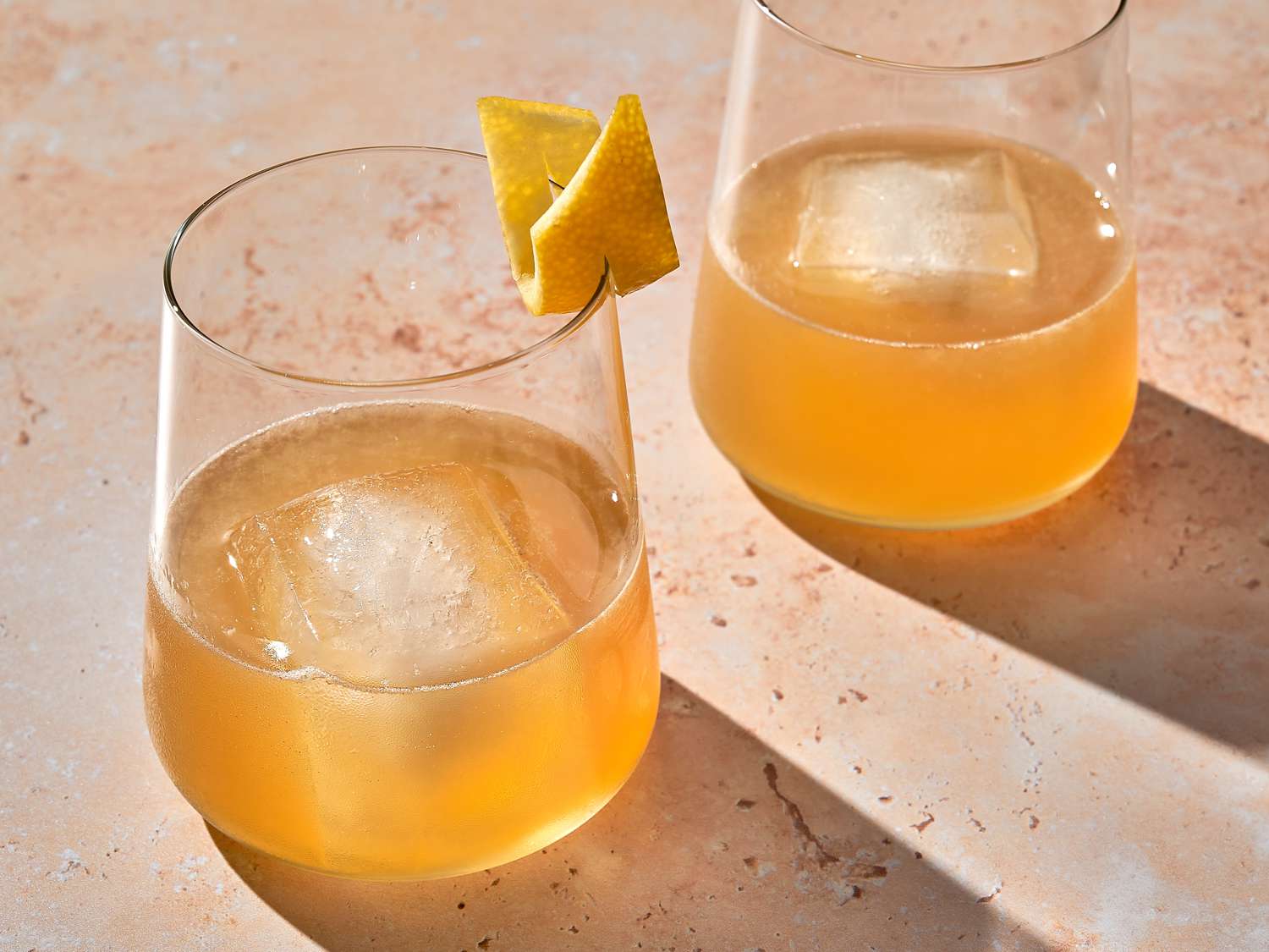 Two gold rush cocktails garnished with lemon peel.