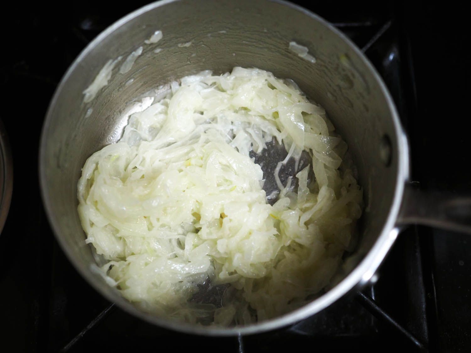 The blanched onions, drained of water, back in the saucepan, showing their pale color.