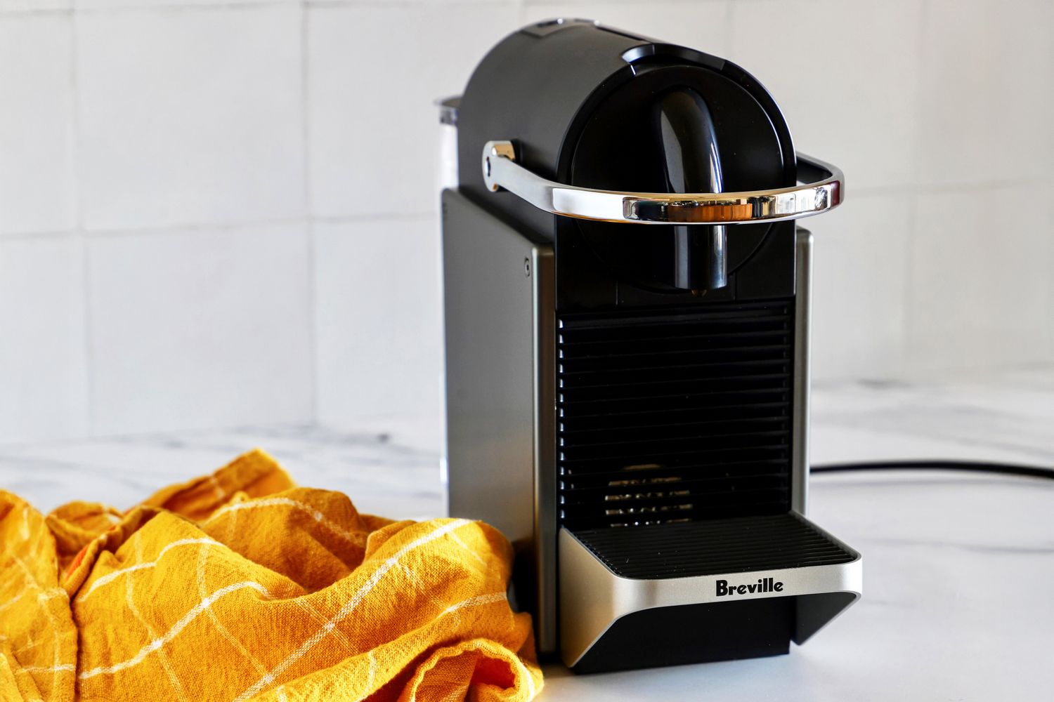 A Nespresso machine on a countertop near a yellow kitchen towel