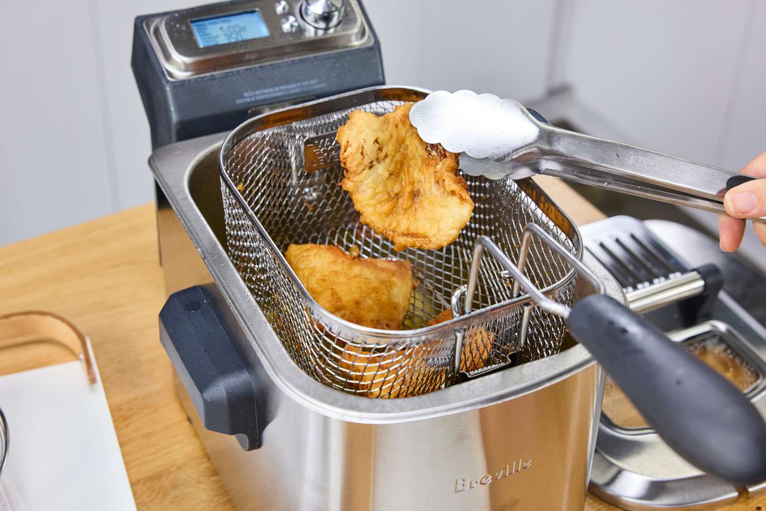 A person fries food in the Breville BDF500XL Smart Fryer
