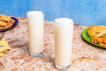 Two Ramos Fizz cocktails, served with brunch food in the background