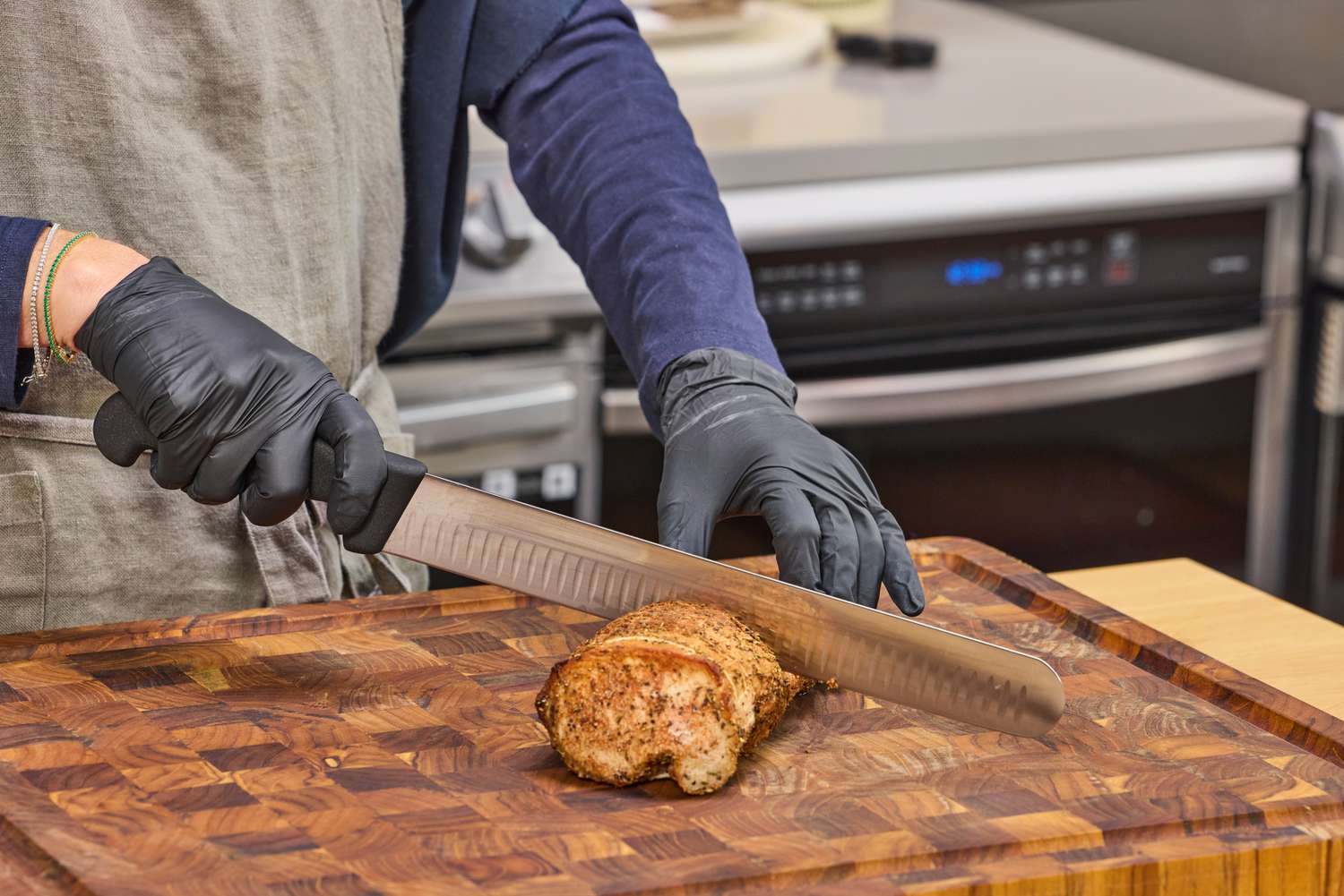 A person slices meat with the Victorinox Fibrox Pro 12-Inch Slicing Knife with Granton Blade