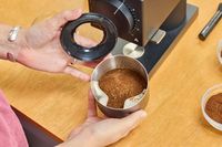 A person holds up a can of coffee ground in the Fellow Ode Gen 2 Coffee Grinder