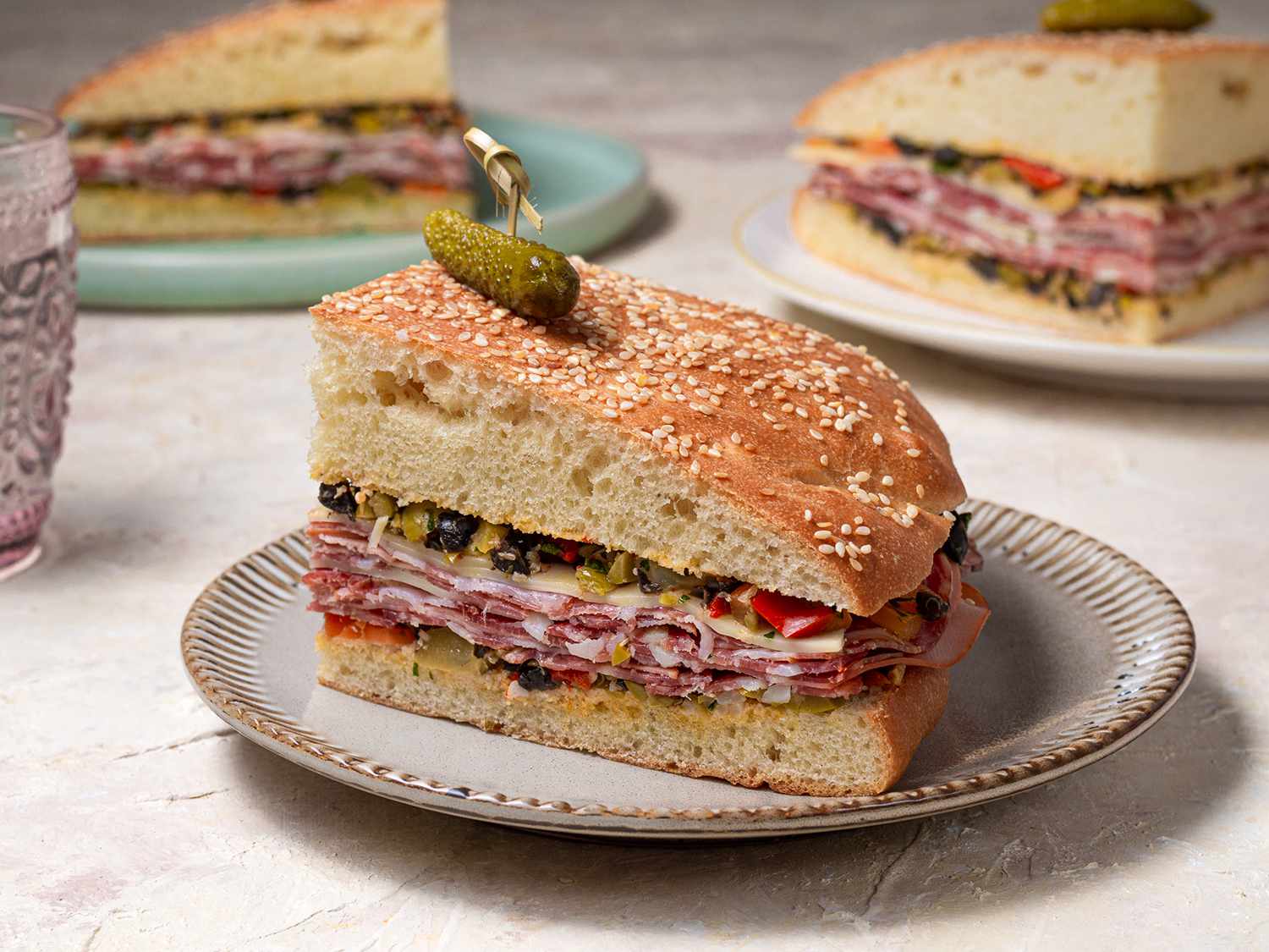 A quarter of a muffuletta sandwich on a ceramic plate.