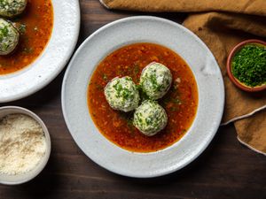 gnudi in a bowl with chives and parmesan cheese on the side