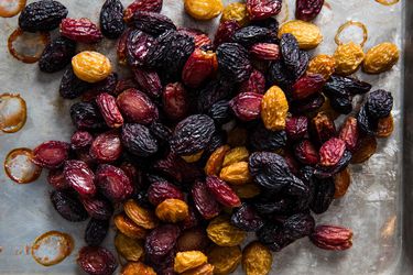 A medley of oven-dried purple, green, and red grapes piled on a sheet pan.
