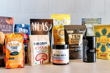 A display of various mushroom coffee product packages from different brands on a table