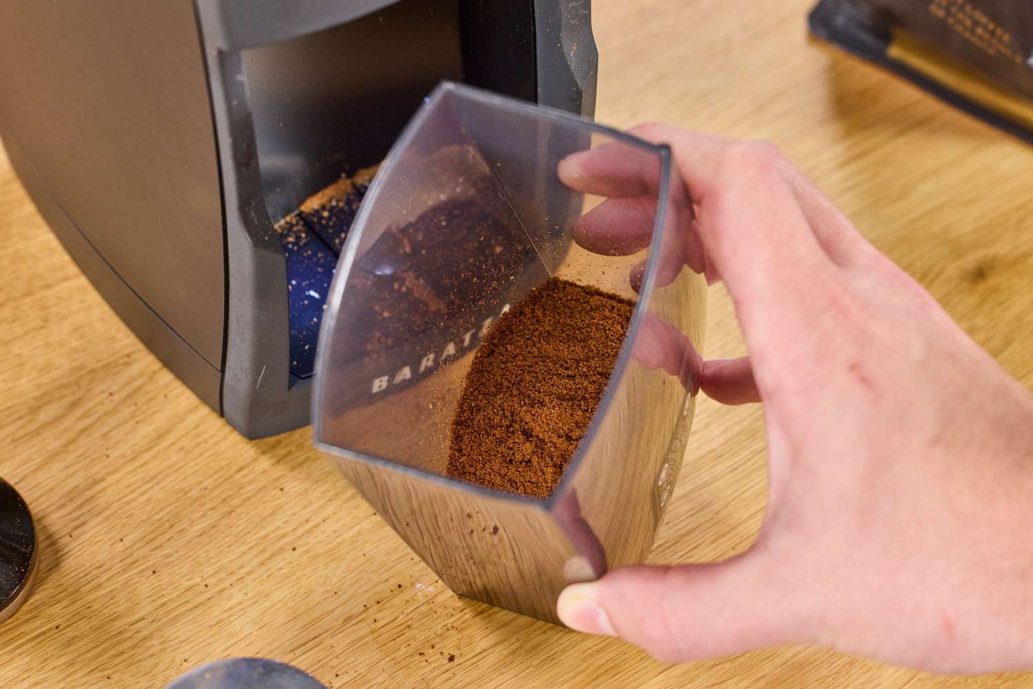 A hand holding a container with ground coffee from the Baratza Encore ESP Pro Coffee Grinder