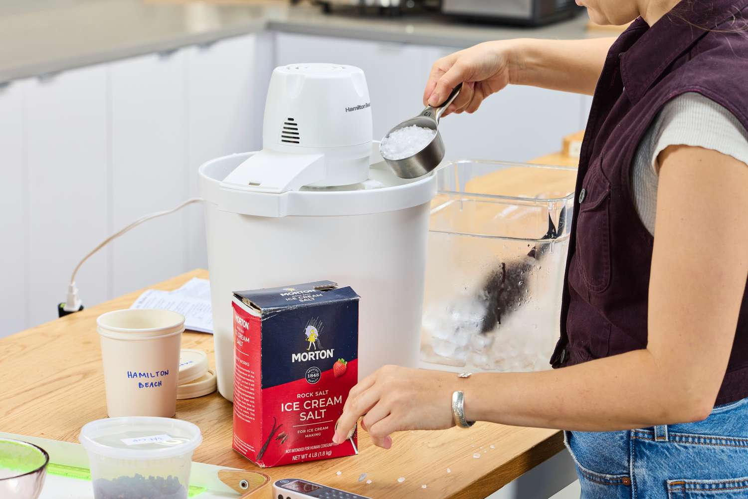 A person adding ice cream salt to the Hamilton Beach Automatic Ice Cream Maker