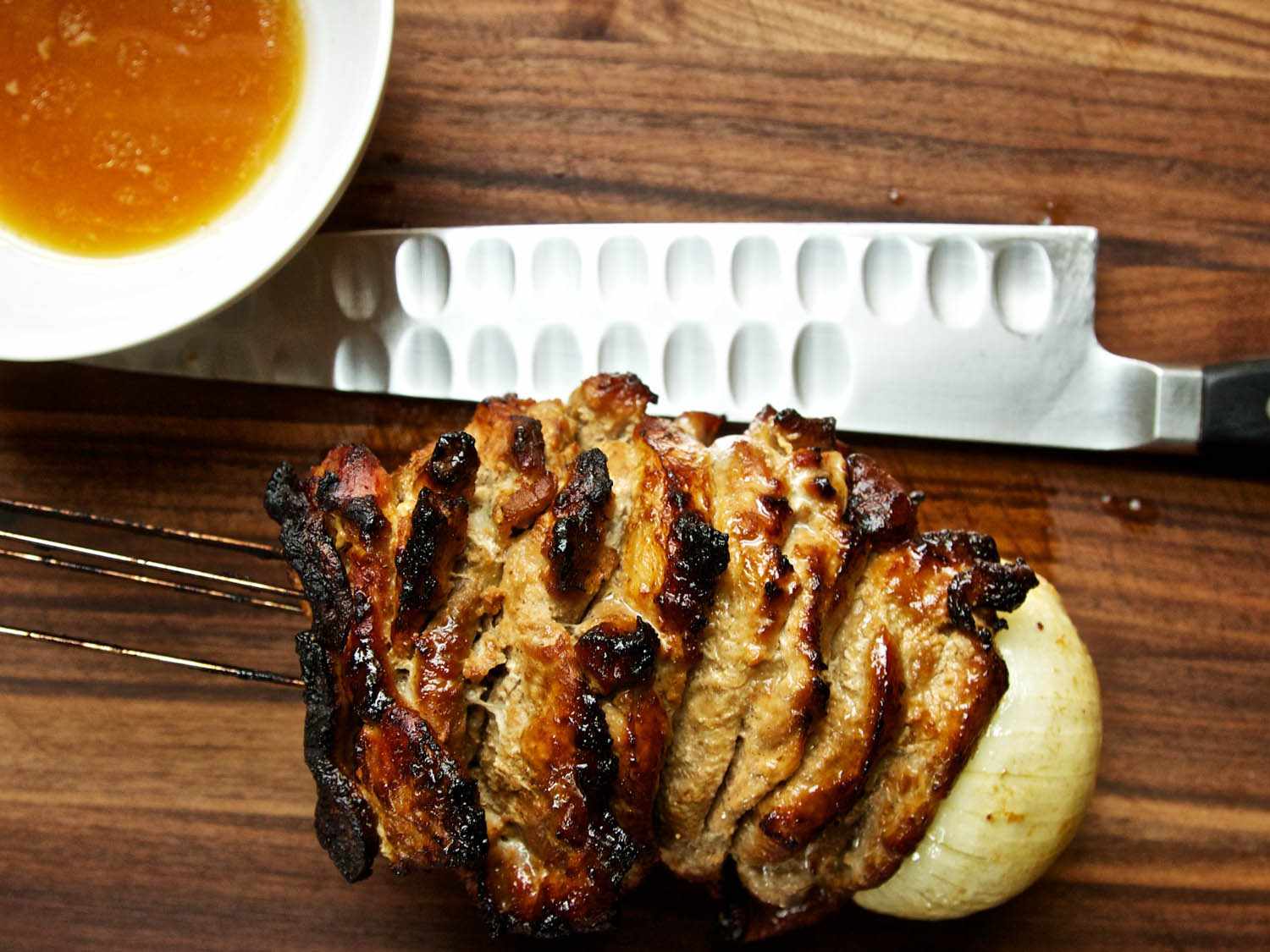 Overhead closeup of a finished shawarma skewer, laid on its side on a cutting board. The exterior looks crispy and well-browned.