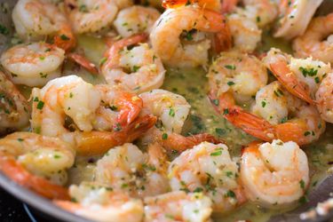 Shrimp scampi in a pan with lots of butter, garlic and parsley. 