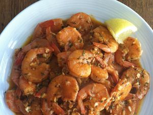a plate of New Orleans-style barbecue shrimp with a lemon wedge. 
