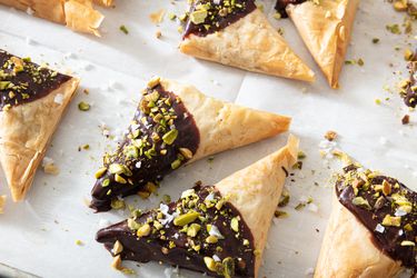 Dubai chocolate triangles arranged on sheetpan topped with pistachio