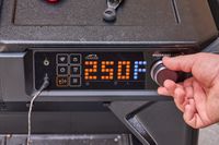 A person turns a dial on the Traeger Woodridge Pro