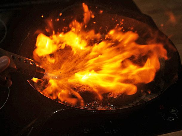 Torching a ribeye steak in a cast iron pan with a propane torch
