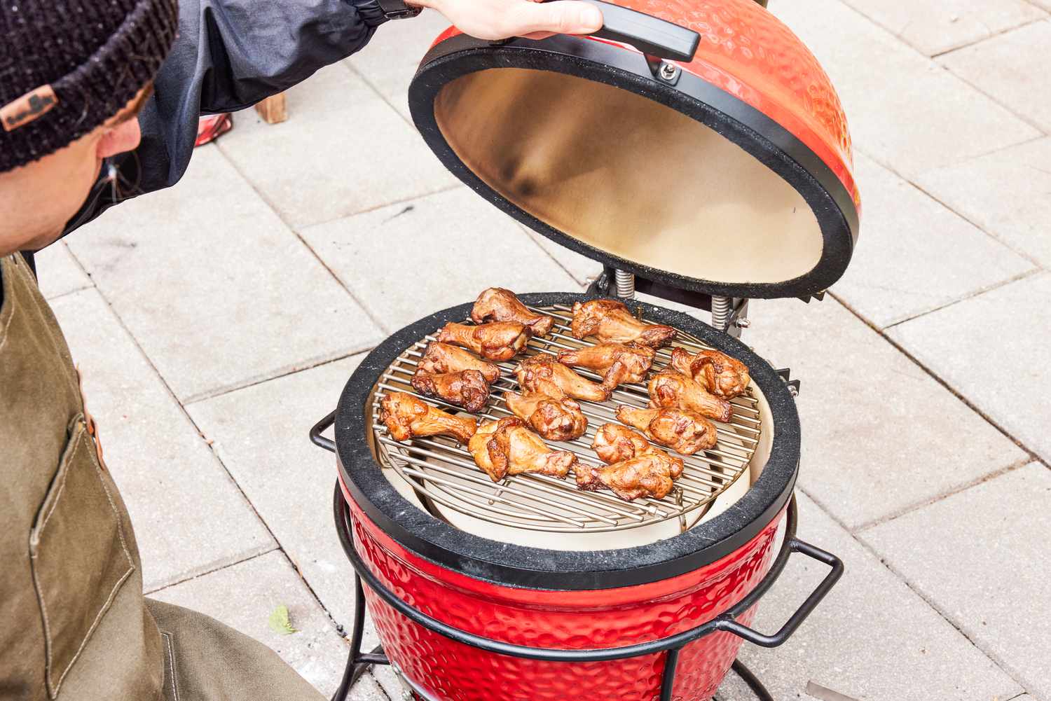 A person cooks chicken in the Kamado Joe KJ13RH 13.5 inch Joe Jr. Charcoal Grill