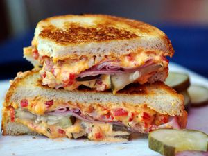 Closeup side view of a halved Grilled Pimento Cheese, Ham, and Homemade Pickles Sandwich.