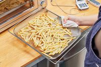 A hand holding a rack of fries to cook in the Breville the Smart Oven Air Fryer