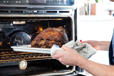 Using a towel to take a pan with a prime rib out of the oven. 