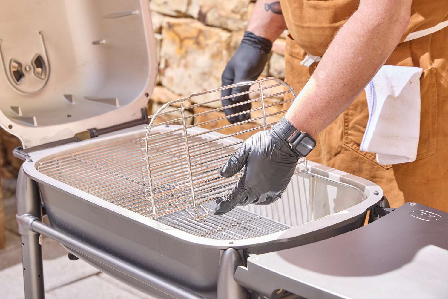 Two hands lifting the rack of the PK Grills Original PK300 Grill & Smoker 