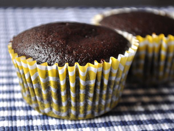 Chocolate-coffee muffins in yellow-and-white paper wrappers, on a blue-and-white gingham surface.