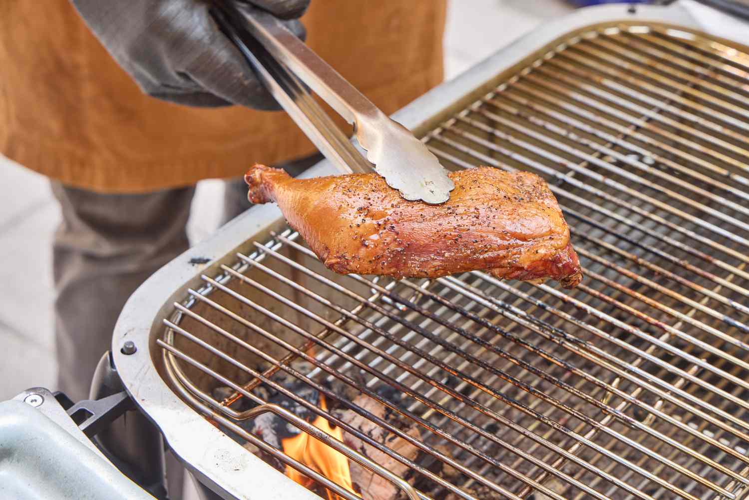 Tongs lifting cooked chicken off of PK Grills Original PK300 Grill & Smoker 