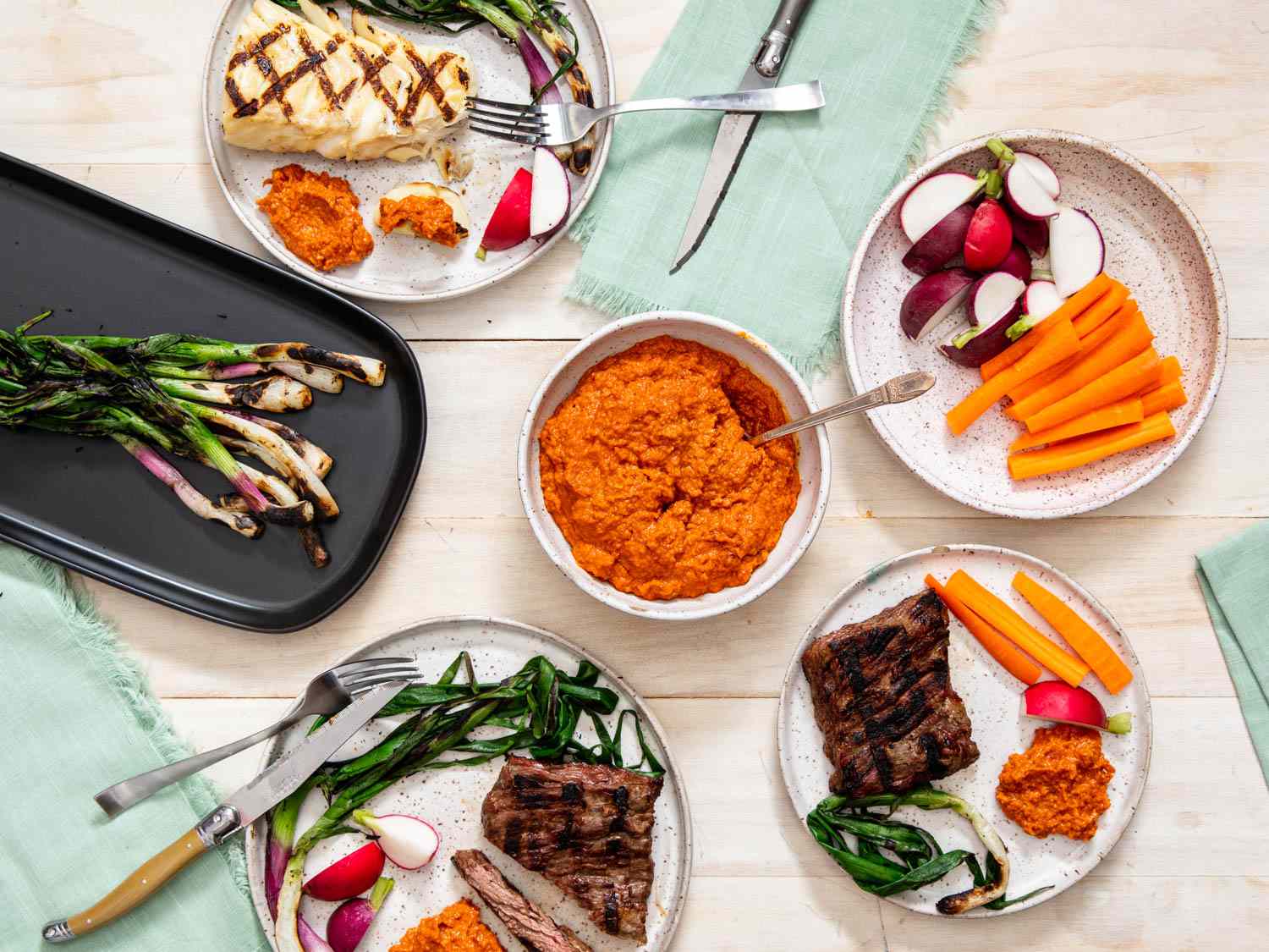 Tablescape of romesco sauce, and dishes to use it with: dip for raw vegetables and with grilled meat.