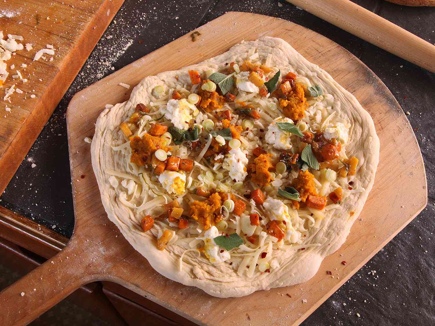 The assembled pizza on a wooden baking peel.