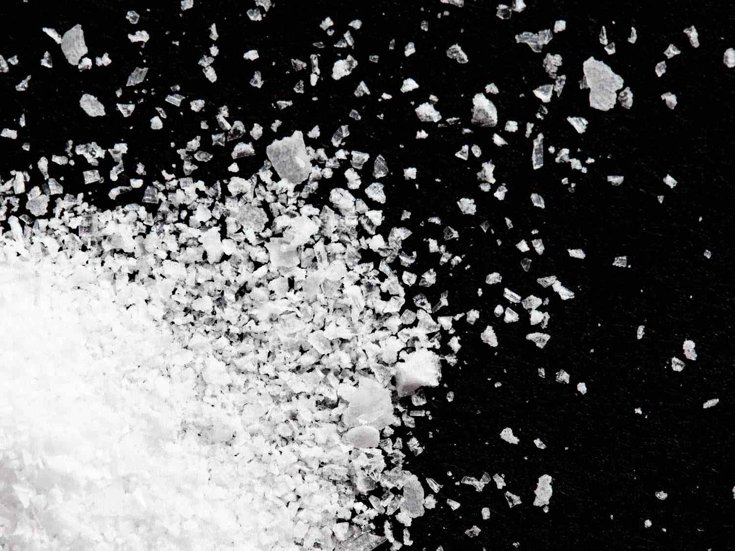 Close up of Diamond Crystal kosher salt on a black surface.