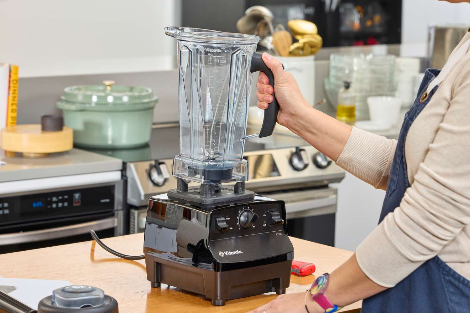 A person lifting a lidless and empty Vitamix 5200 Professional-Grade Blender by its handle