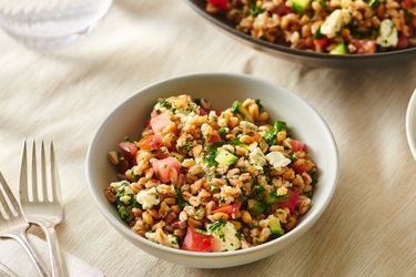 Serving of farro salad with blue cheese, pine nuts, and tomatoes served inside a bowl