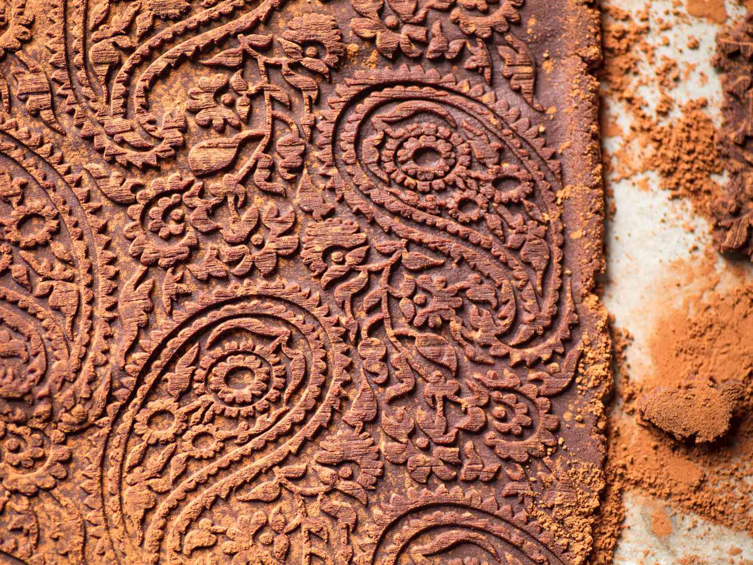 Oreo cookie dough being rolled out with an embossed pin for decoration. 