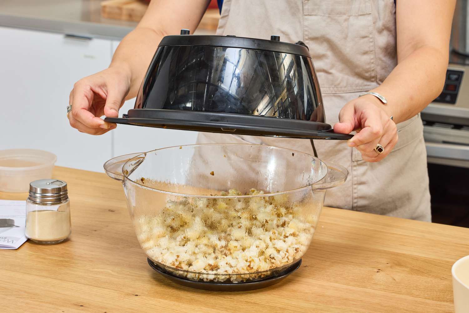 A person removes the lid on the West Bend Stir Crazy Electric Hot Oil Popcorn Popper