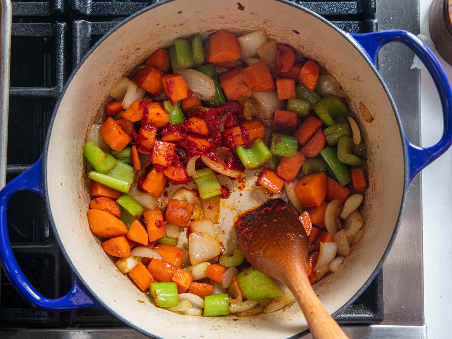 Mirepoix cooking in the bottom of an enamel cast iron Dutch oven.