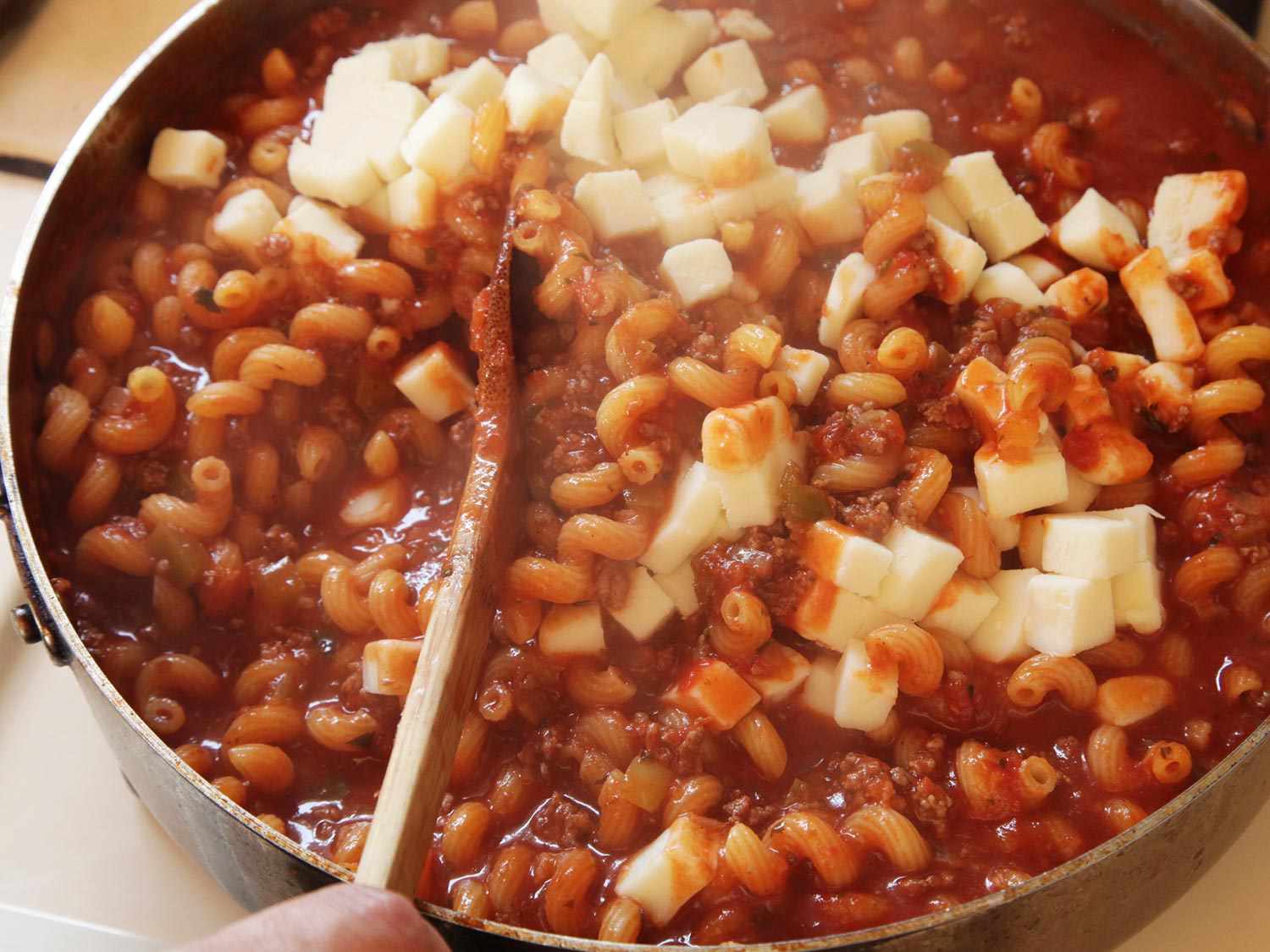 Cubes of mozzarella being stirred into the casserole.